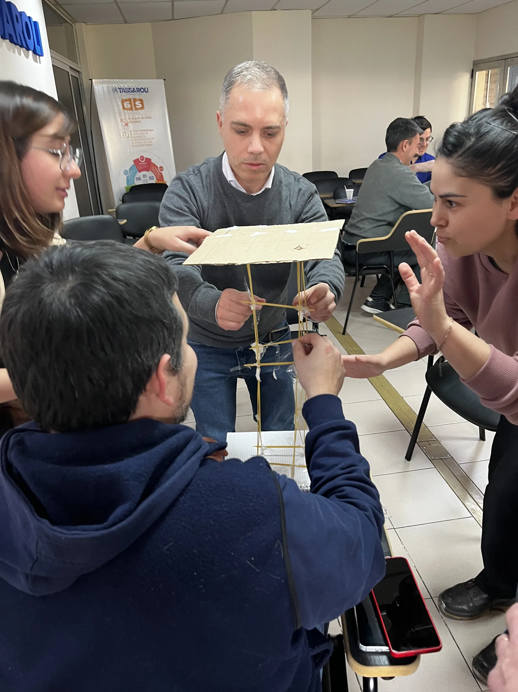 Equipo construyendo una torre con fideos y cinta durante una dinámica